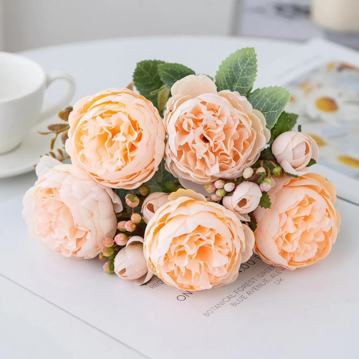 Silk artificial peony bouquet in champagne colour on a table.