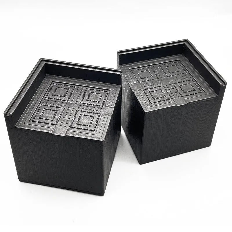 Four black circular plastic bed foot mats for furniture levelling and floor protection
