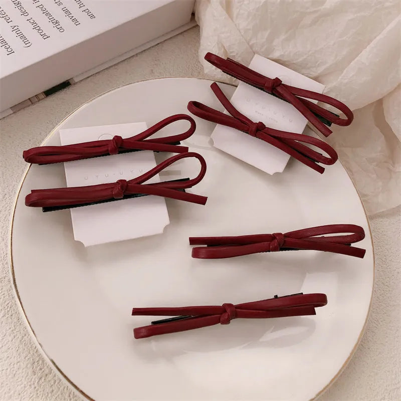 Wine red leather bow barrette hair clip on a white background.