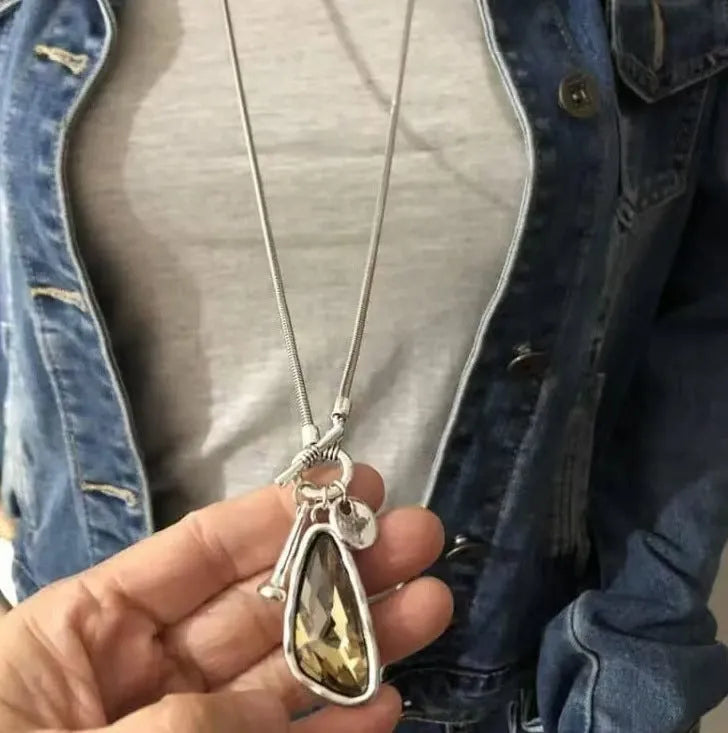 Long alloy necklace with geometric pendant on a snake bones chain, shown in blue water drop colour.