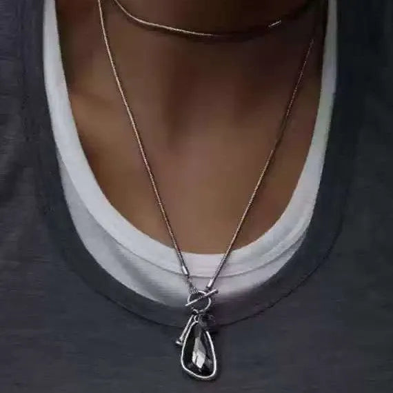 Long alloy necklace with geometric pendant on a snake bones chain, shown in blue water drop colour.