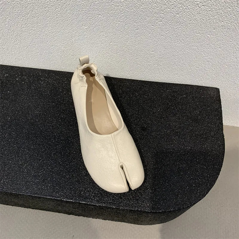 Women's black chunky heel pump with split toe and round toe design on a neutral background.