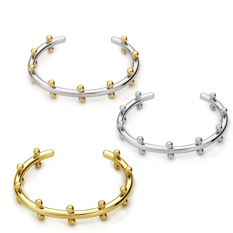 Stainless steel C-shaped bean bead with textured rivet detail in gold, silver, and two-tone finishes.