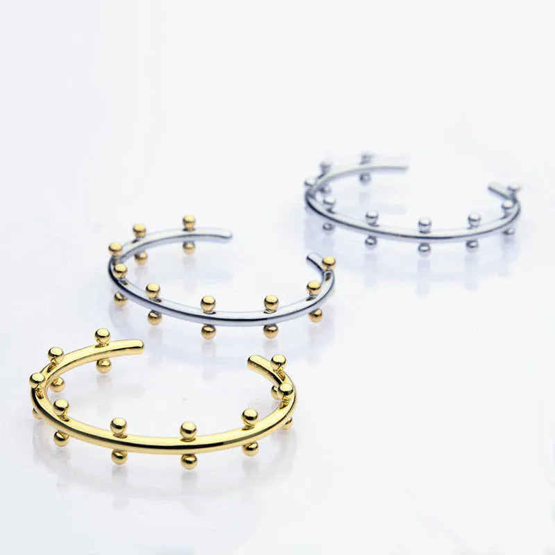 Stainless steel C-shaped bean bead with textured rivet detail in gold, silver, and two-tone finishes.