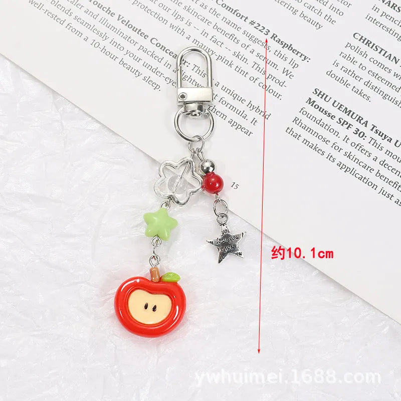 Plastic resin fruit pattern phone charm keychain pendant with apple and strawberry designs on a white rope.