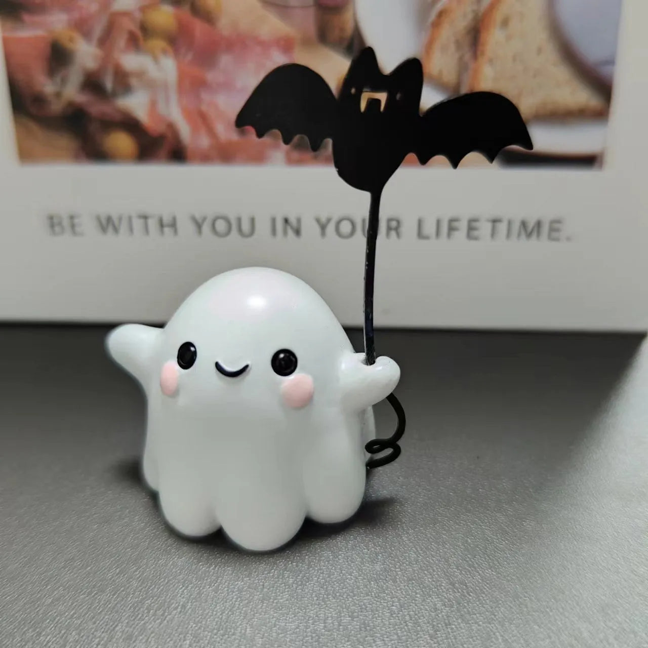 Miniature resin statue of a ghost walking a dog that is holding a bat, a Halloween decoration.