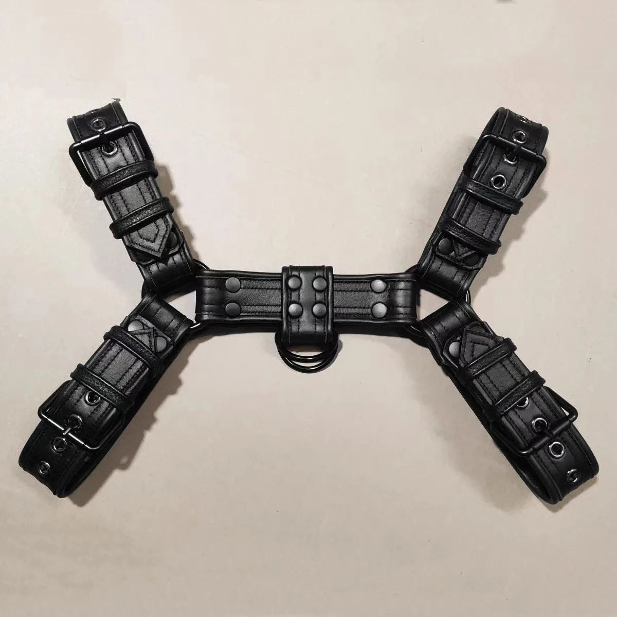 Black leather chest strap with metal buckle and rivets laid flat