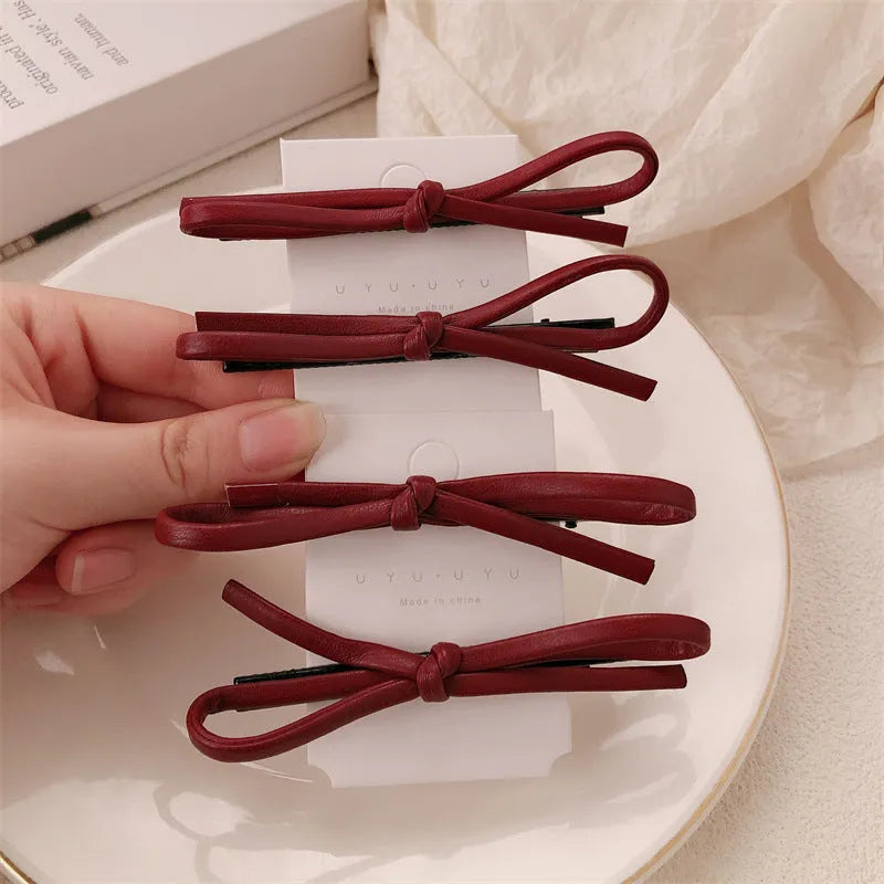 Wine red leather bow barrette hair clip on a white background.
