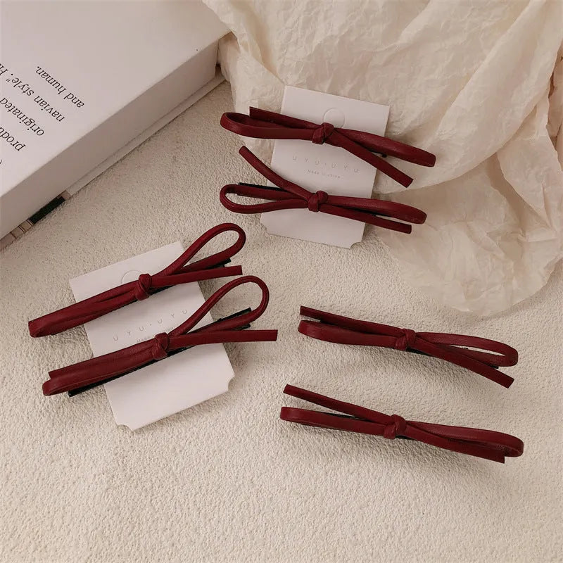 Wine red leather bow barrette hair clip on a white background.