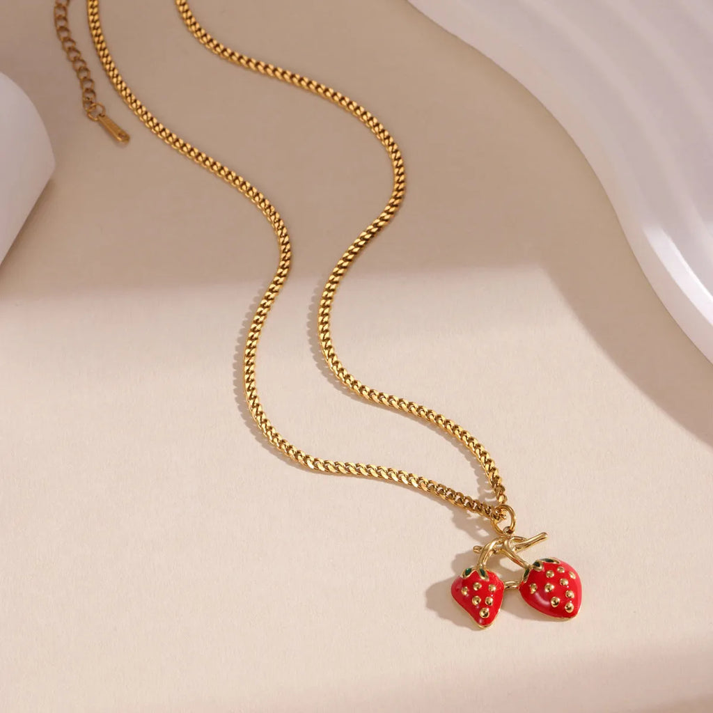 Close-up of a red stainless steel strawberry charm necklace on an alloy chain.