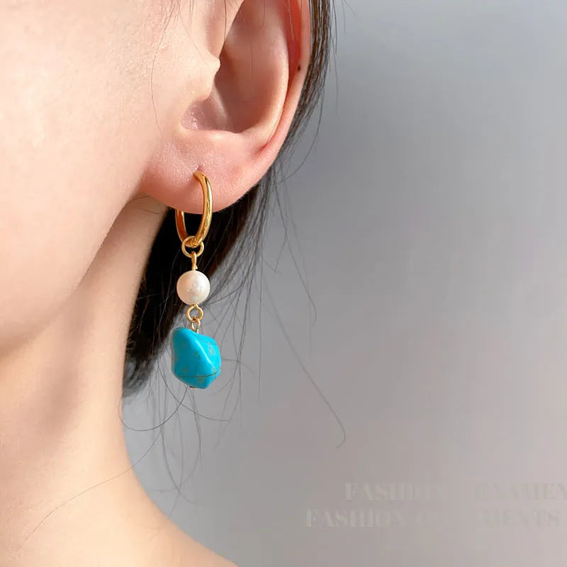 A pair of irregular shaped geometric copper ear clip earrings featuring turquoise stones and cultured pearls.