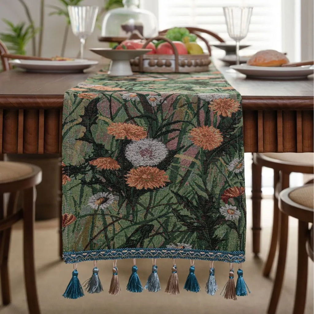 Beige jacquard table runner with floral pattern and long tassels laid flat on a table.