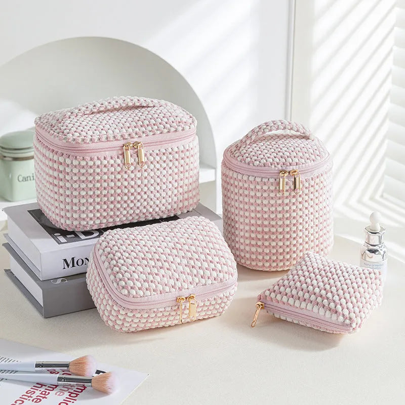 Four cube-shaped flannelette makeup bags in different colours for travel storage