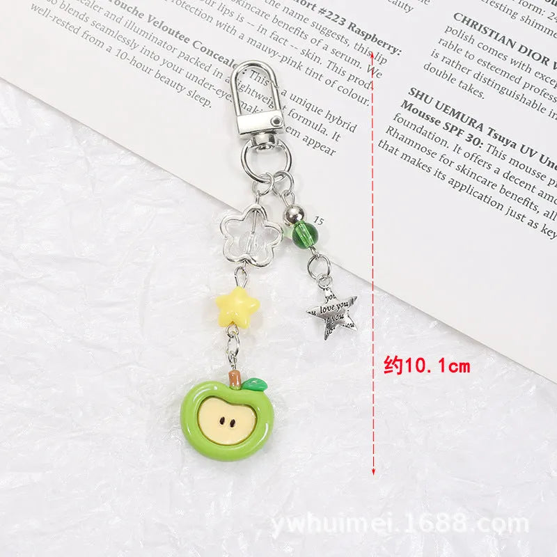 Plastic resin fruit pattern phone charm keychain pendant with apple and strawberry designs on a white rope.