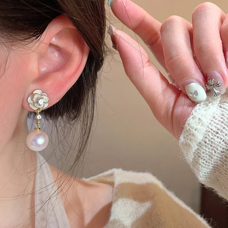 Close-up of women's camellia flower stud earrings in alloy with floral design.