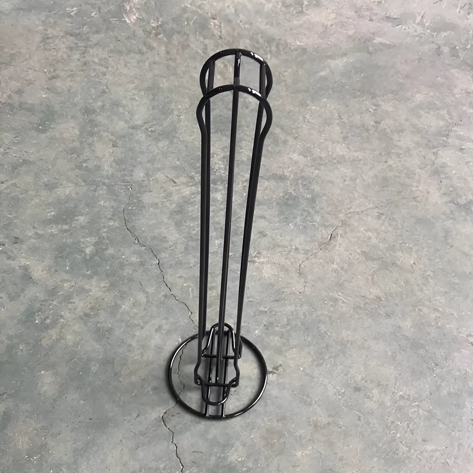 Black wrought iron coffee capsule storage rack holding pods on two shelves.