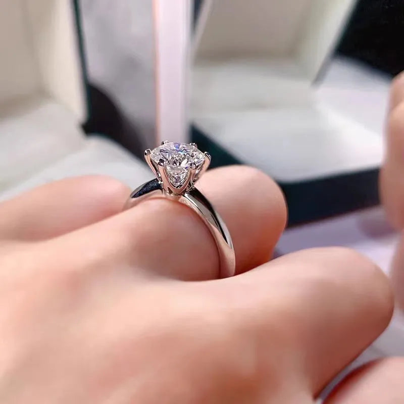 White gold plated geometric ring with a six-claw zircon setting on a hand.