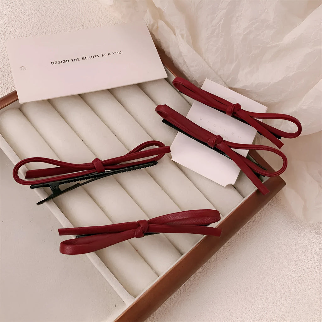 Wine red leather bow barrette hair clip on a white background.