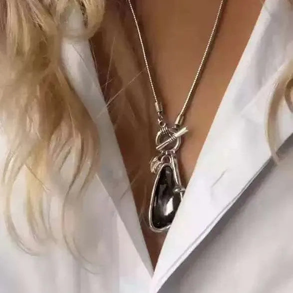 Long alloy necklace with geometric pendant on a snake bones chain, shown in blue water drop colour.