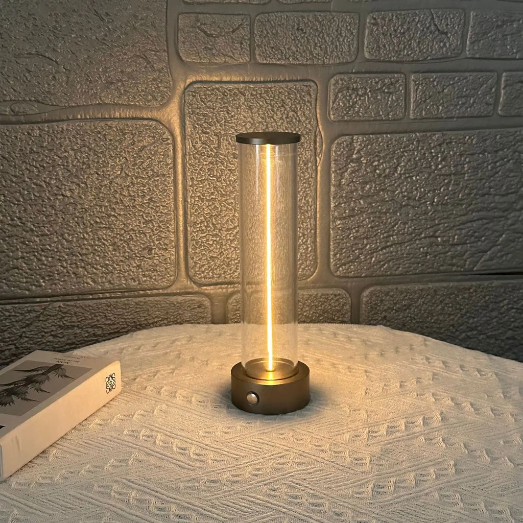 Glass cylindrical LED night light with magnetic base on a metal surface, showing USB charging port.
