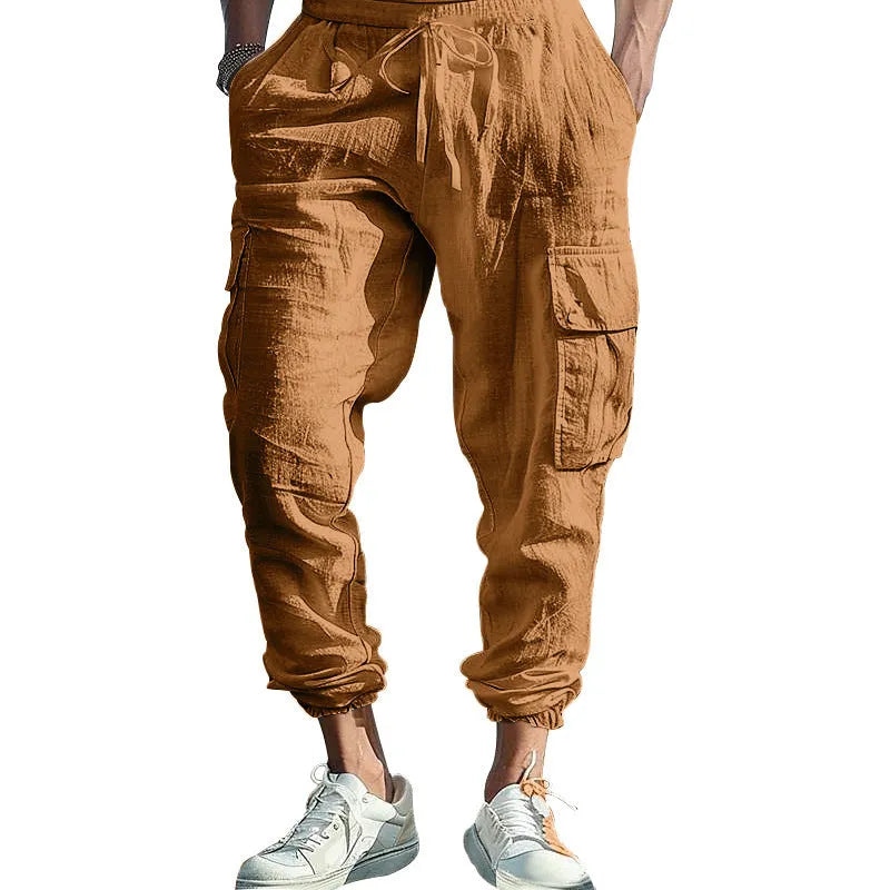 Man wearing loose, ankle-tied linen trousers in a solid colour with visible pockets.