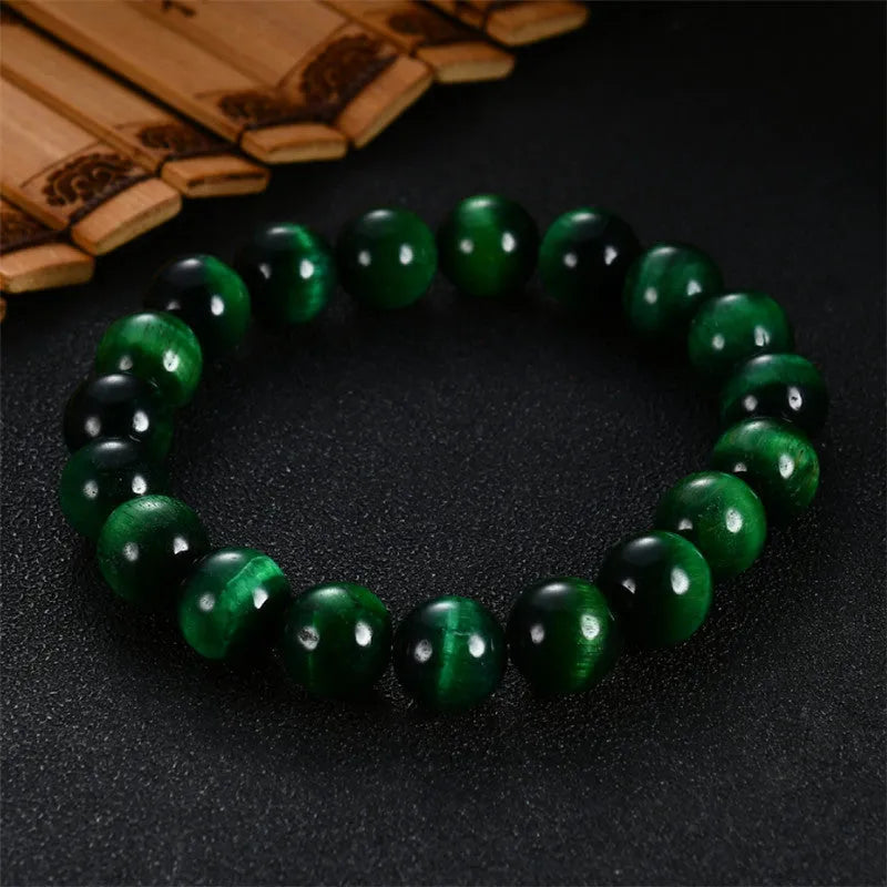 Polished green tiger eye stone bead bracelet with geometric beads on a wrist.