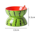 Ceramic elevated cat bowl with tilted surface in a colourful fruit pattern, showing its height and wide design.