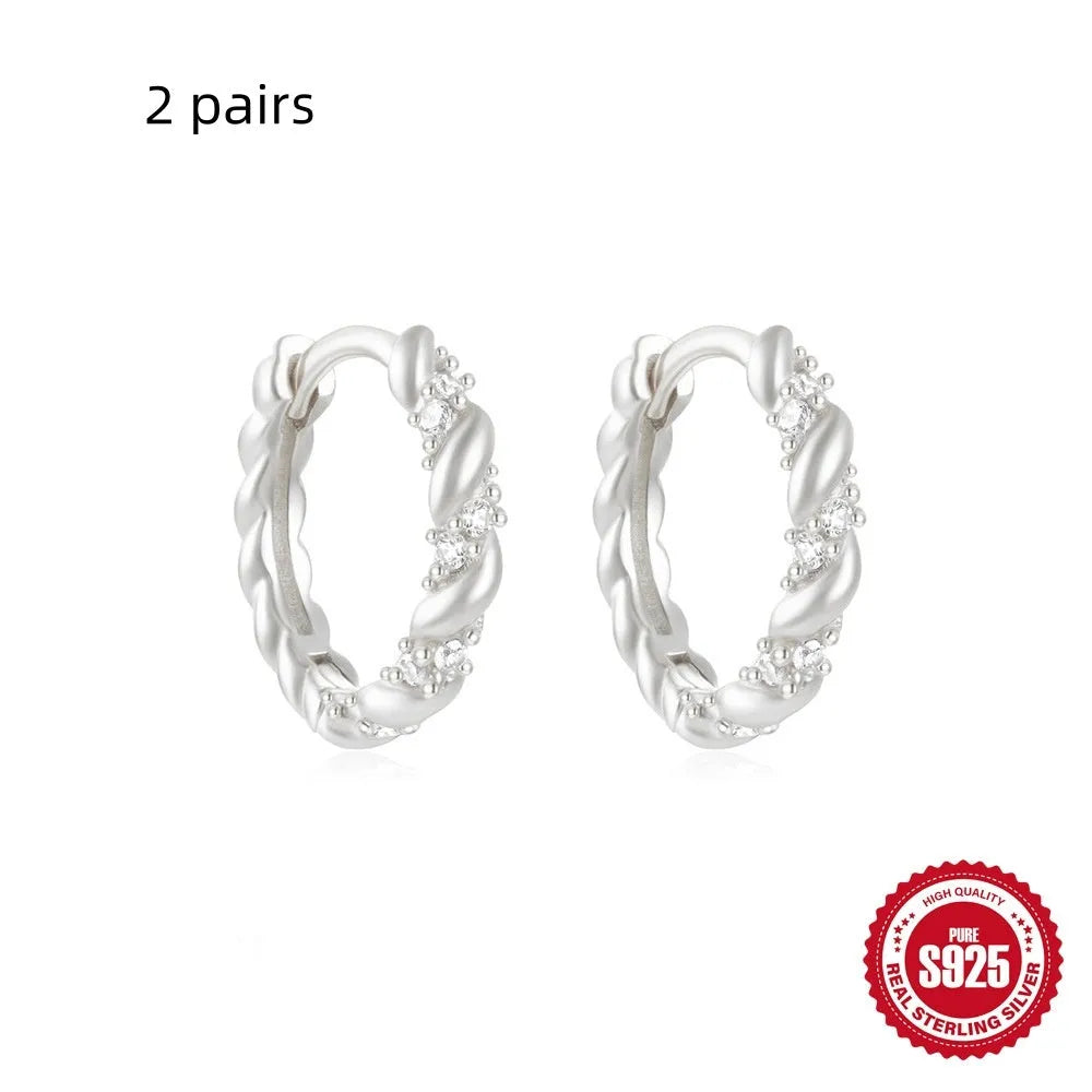 Sterling silver geometric stud earrings with a small round shape and classic diamond detail on a white background.