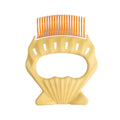 Shell-shaped plastic pet grooming comb with bent wire bristles and anti-slip handle in assorted colours.