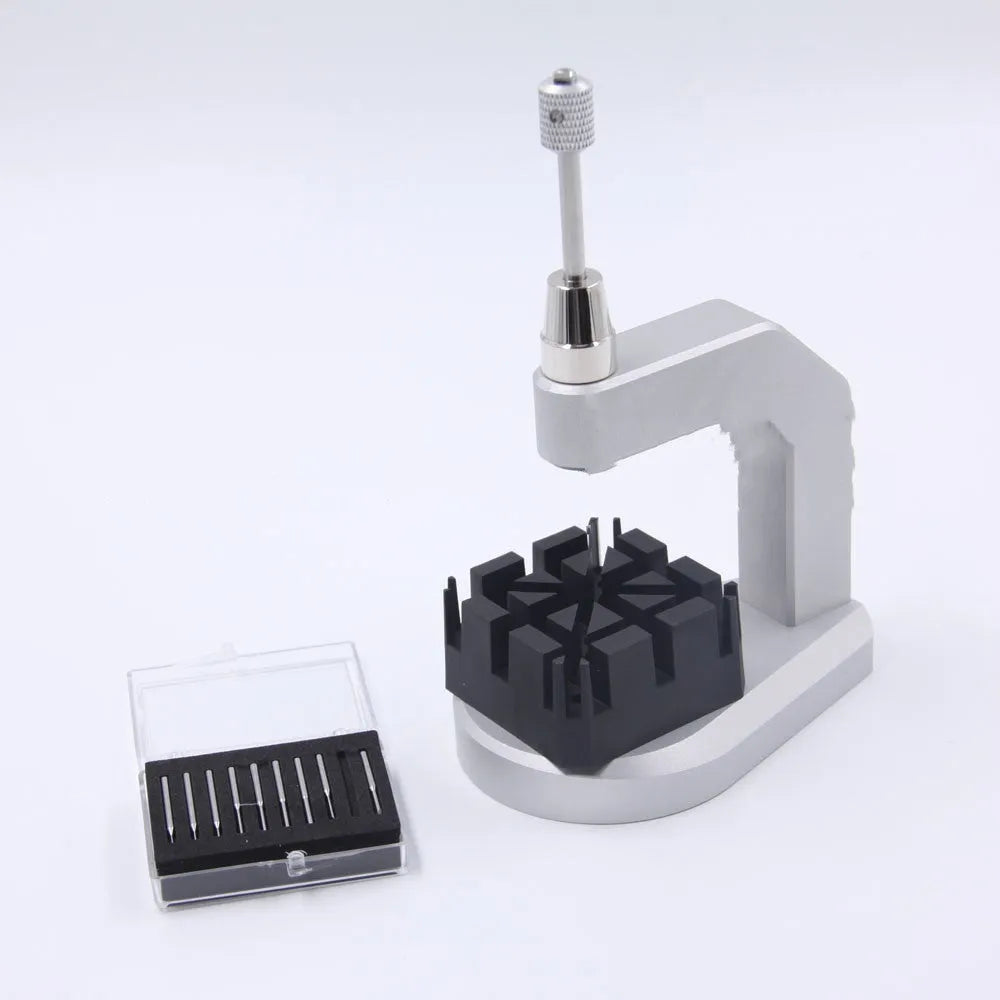 Silver tool steel multi-purpose press strap removal tool for watches and electronics on a workshop surface.