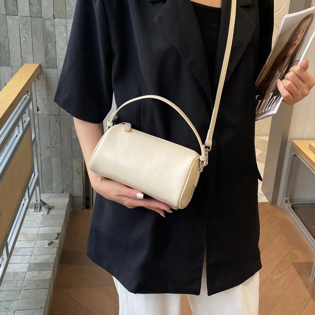 Vegetable-tanned leather crossbody phone bag with cylindrical shape and visible sewing thread detailing