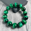 Polished green tiger eye stone bead bracelet with geometric beads on a wrist.