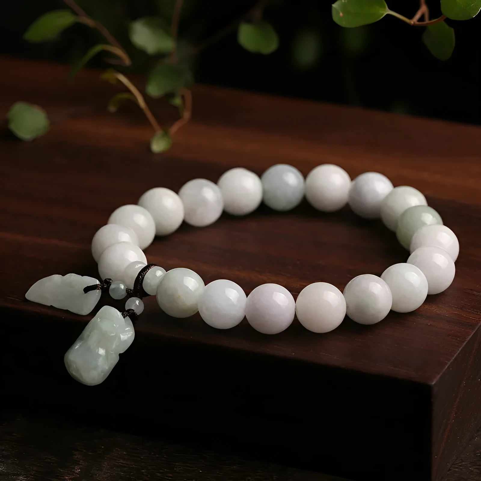 Natural green jade bracelet with a geometric pendant charm on a wrist.