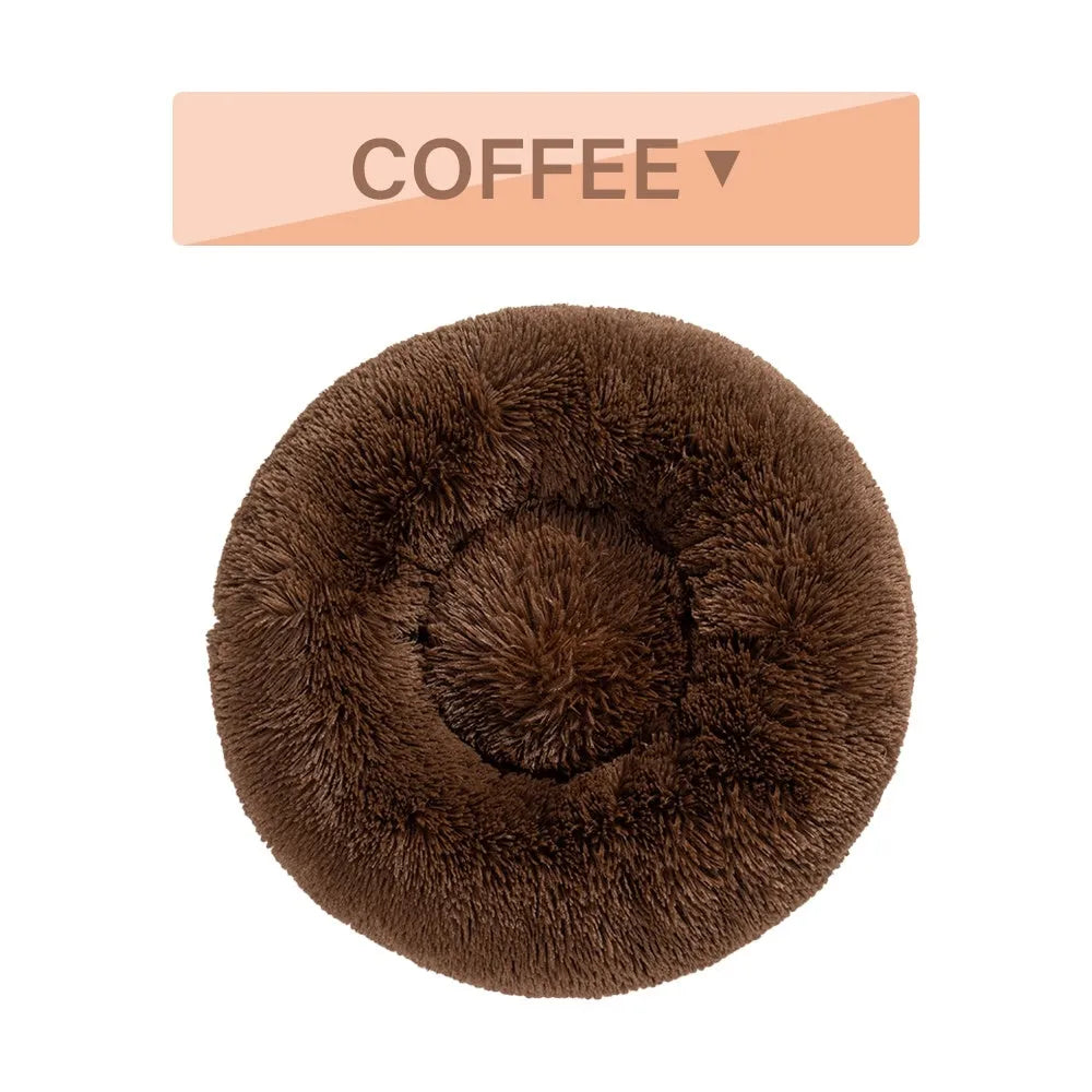Fluffy donut-shaped dog bed in long plush material, shown in a light grey colour with a raised edge.