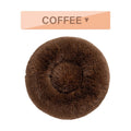 Fluffy donut-shaped dog bed in long plush material, shown in a light grey colour with a raised edge.