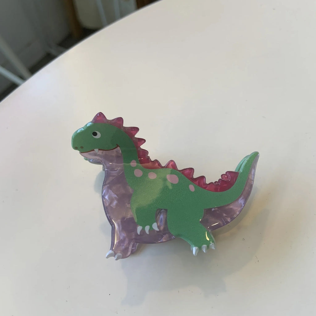 Acrylic dinosaur jaw grip hair clip showing six colour variations with prehistoric creature designs