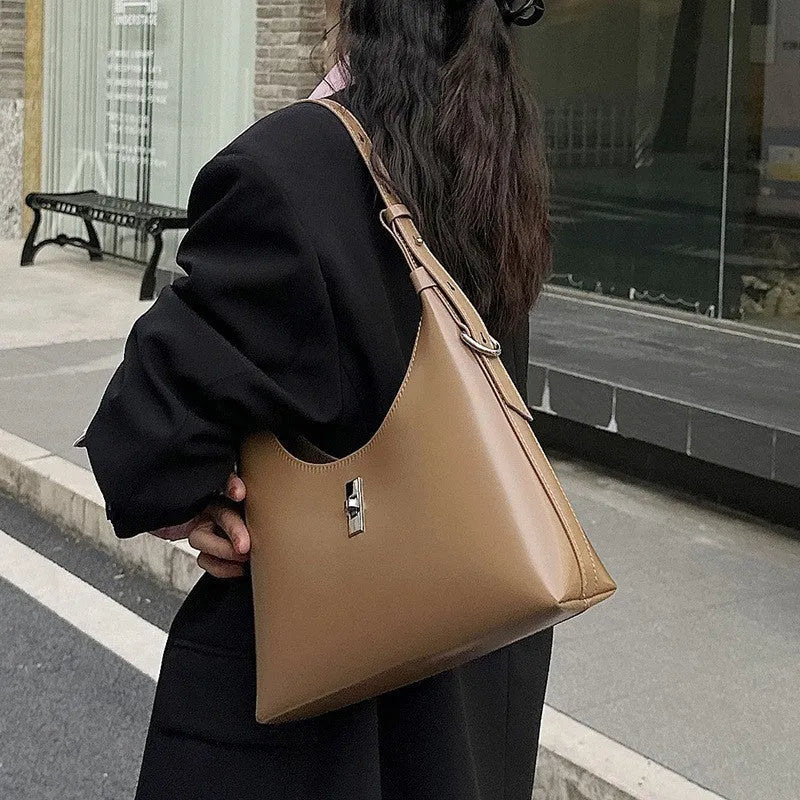 A soft genuine leather dumpling-shaped crossbody shoulder bag in a street style, shown with internal phone pocket.