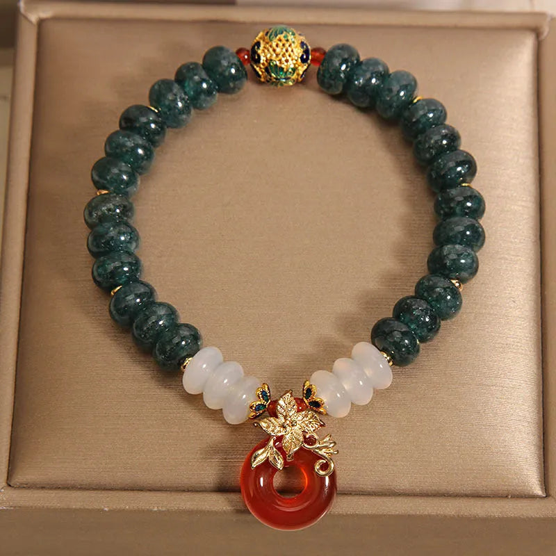 Blue water jade bead bracelet with red agate peace buckle closure and rhinestone details