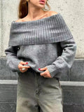 Woman wearing a grey off-the-shoulder strapless sweater with a 3D textured pattern.