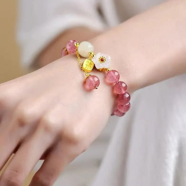 Handcrafted strawberry quartz crystal bracelet with peach blossom design on wrist