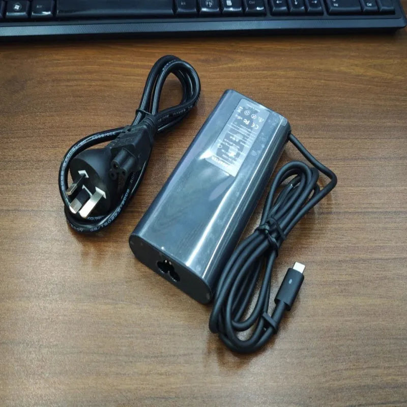 Black 65W Type-C laptop power adapter with multiple international power cords for UK US EU AU and ZA plugs.