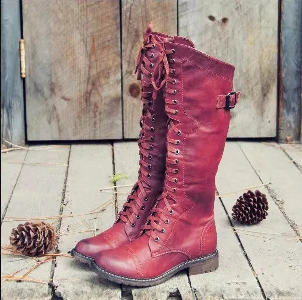 Black chunky heel high leg boots with a round toe and short stout heel on a plain background.