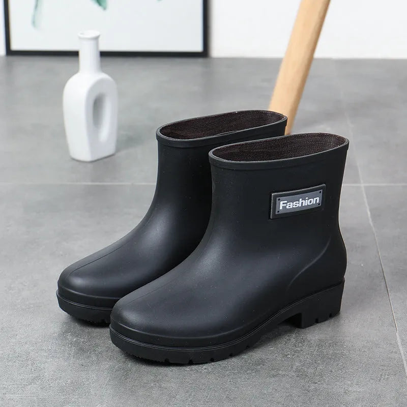 Women's mid-calf PVC rain boot in black on a wet surface.