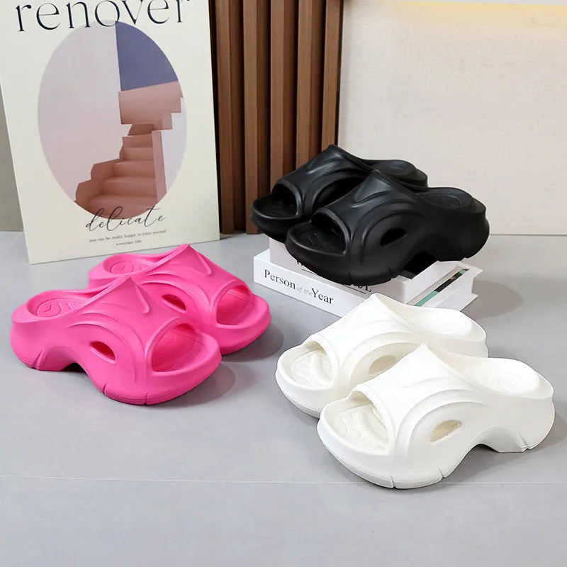 Women's white EVA slippers with a thick sole and round toe on a sandy beach.