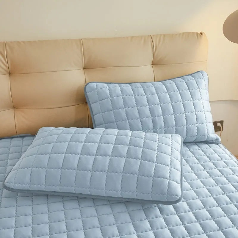 A washed cotton waterproof fitted sheet in a neutral colour, shown fitted neatly on a mattress corner.
