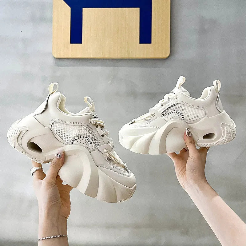 Women's beige sneakers with a cross shoulder strap and thick rubber sole on a white background.