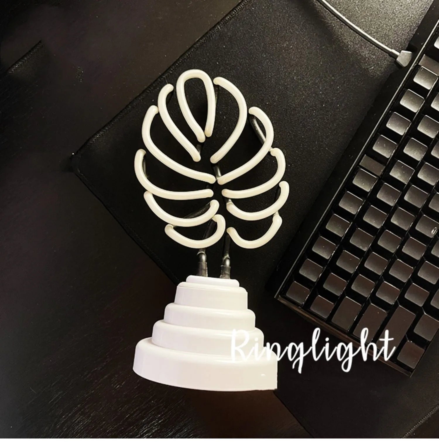 White bamboo-shaped desktop lamp with green light tube on a wooden desk.