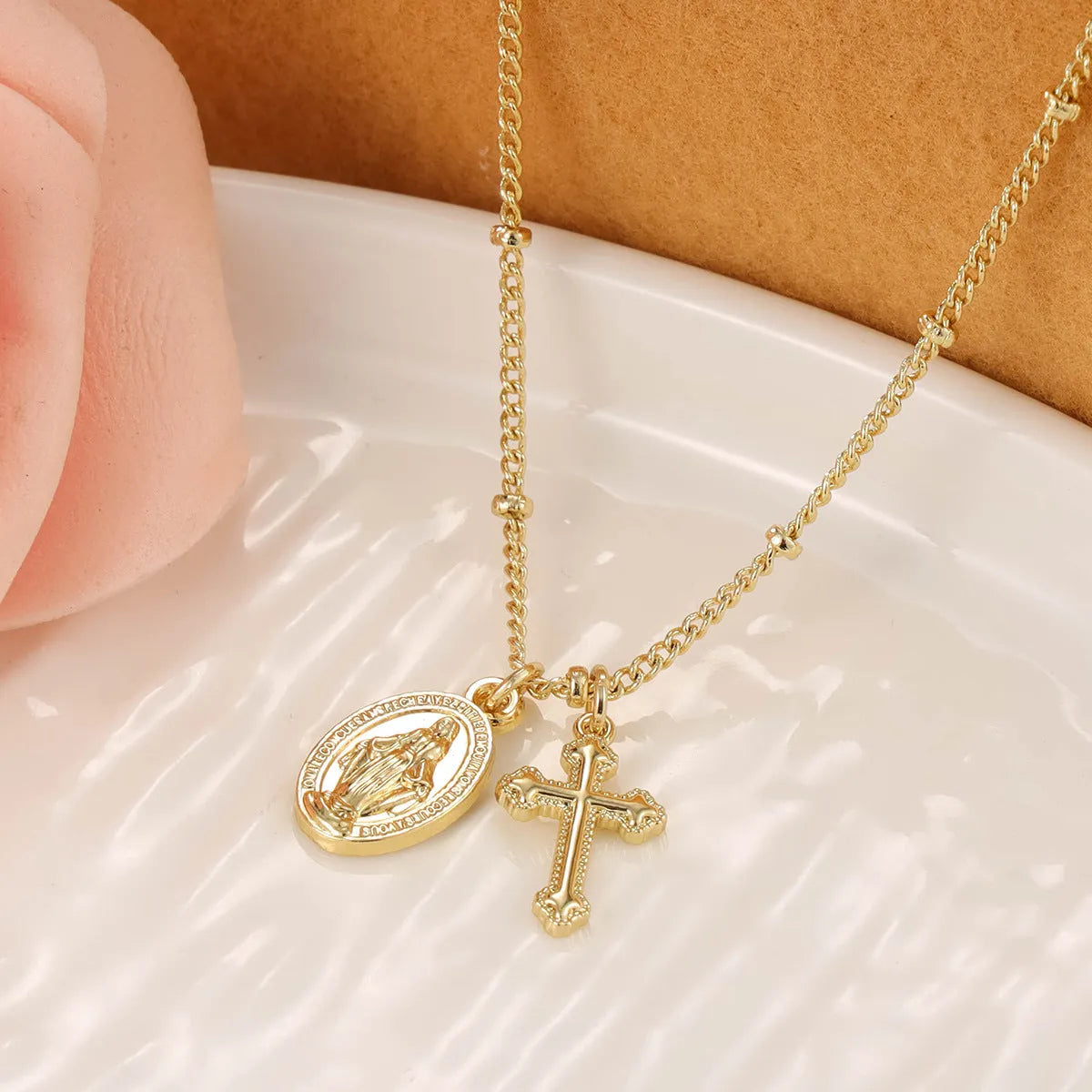 Geometric shaped gold tone pendant necklace with Cross and Virgin Mary ornament.