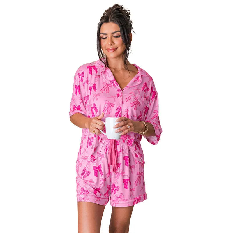 Women's pink bow print two-piece pajama set with top and trousers on a hanger.