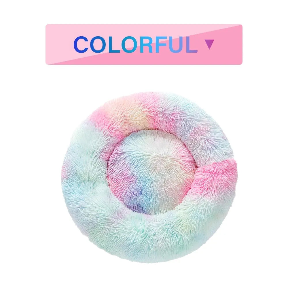 Fluffy donut-shaped dog bed in long plush material, shown in a light grey colour with a raised edge.